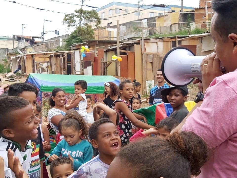 Subprefeito, Gilmar Souza Santos, fala em um megafone. Enquanto isso, crianças e alguns adultos sorriem para ele. 